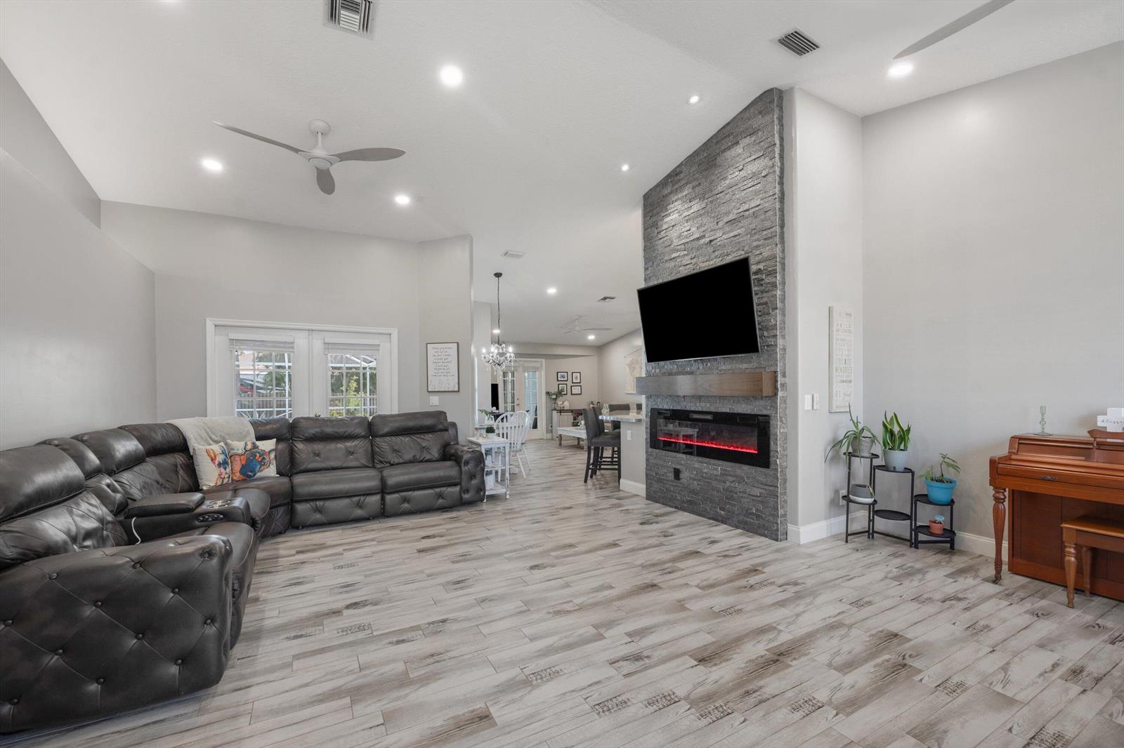 A living room features a stone fireplace, a large sectional sofa, and wood-look tile flooring — 14862 85th Road N, FL 33470, FL