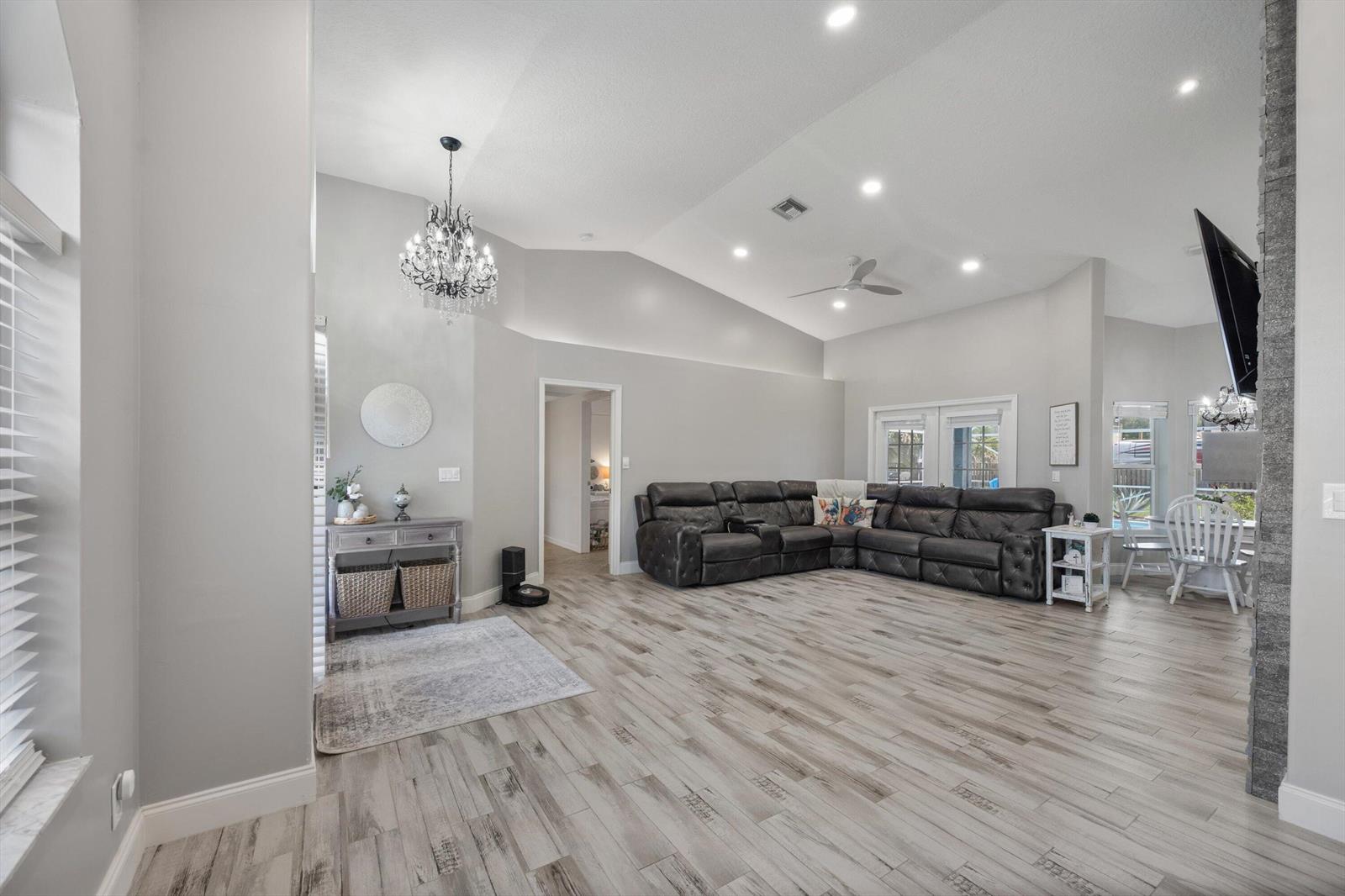 A spacious living room features vaulted ceilings, gray wood-look tile flooring, and a dark sectional sofa — 14862 85th Road N, FL 33470, FL