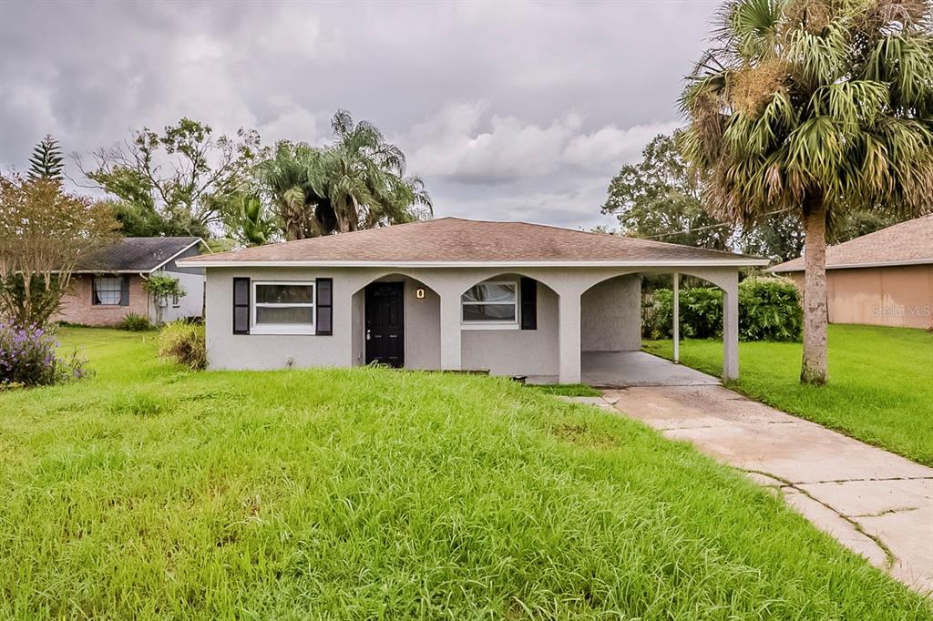 A single-story house with a carport, arched entryway, and a large front lawn — 28042 LOIS DRIVE, TAVARES, FL