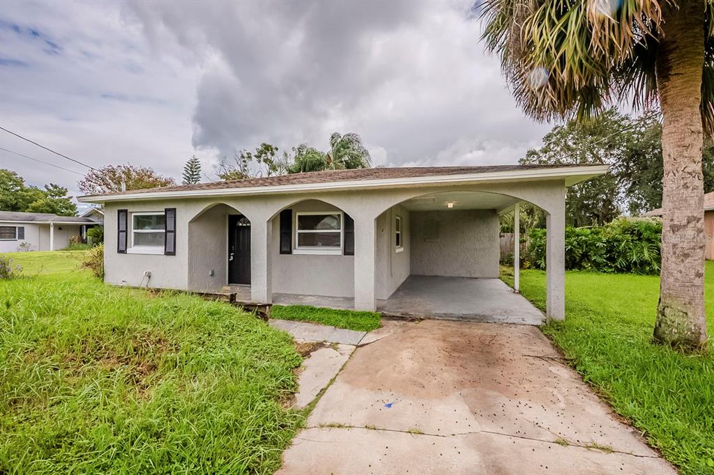 A single-story house with a carport, arched entryway, and a concrete driveway — 28042 LOIS DRIVE, TAVARES, FL