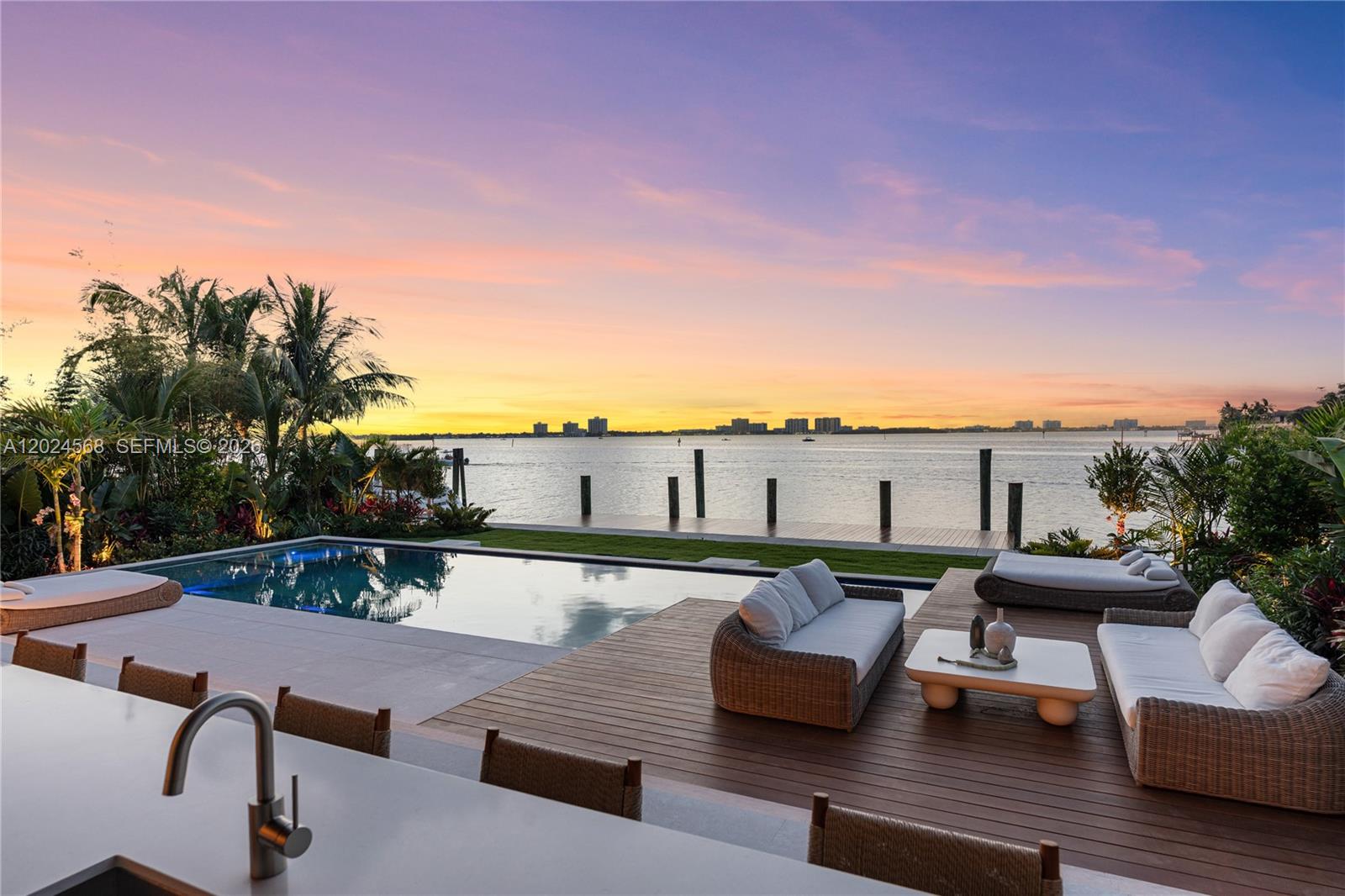 A waterfront patio features a swimming pool, wooden decking, outdoor seating, and a sunset view — 857 N Shore Dr, Miami Beach FL 33141, MIAMI BEACH, FL