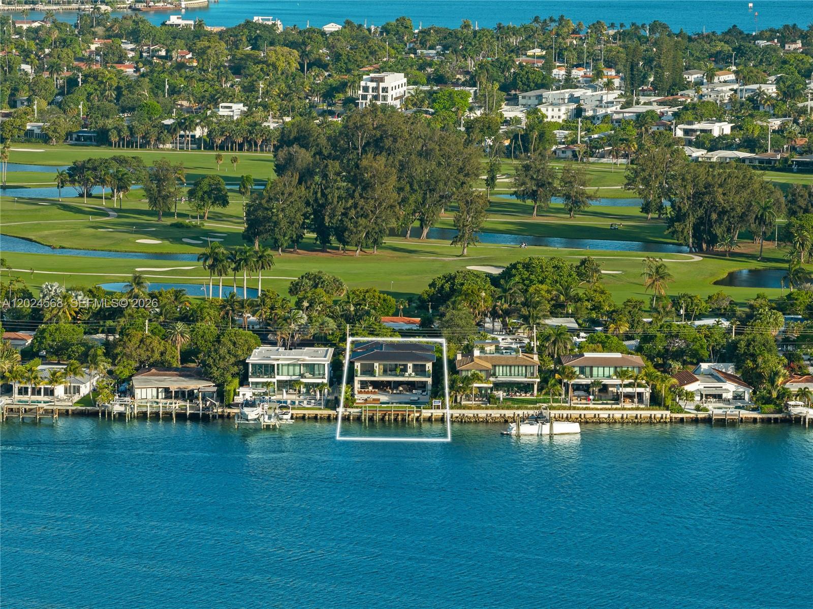 An aerial view shows a waterfront house with a pool and dock on a golf course — 857 N Shore Dr, Miami Beach FL 33141, MIAMI BEACH, FL