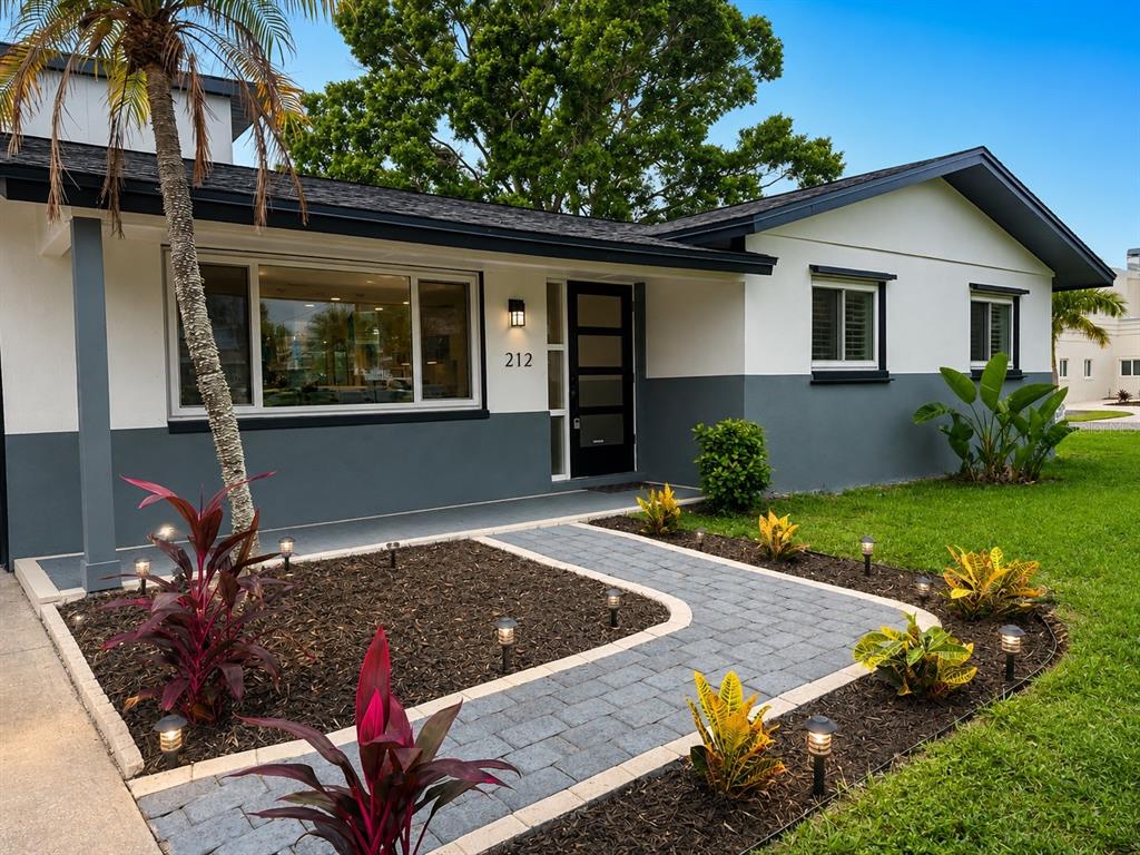 A single-story house with a two-tone exterior, a paved walkway, and a palm tree — 212 DRIFTWOOD PLACE, PALM HARBOR, FL