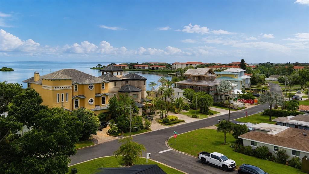 An aerial view shows a large yellow waterfront house next to a street with cars — 212 DRIFTWOOD PLACE, PALM HARBOR, FL