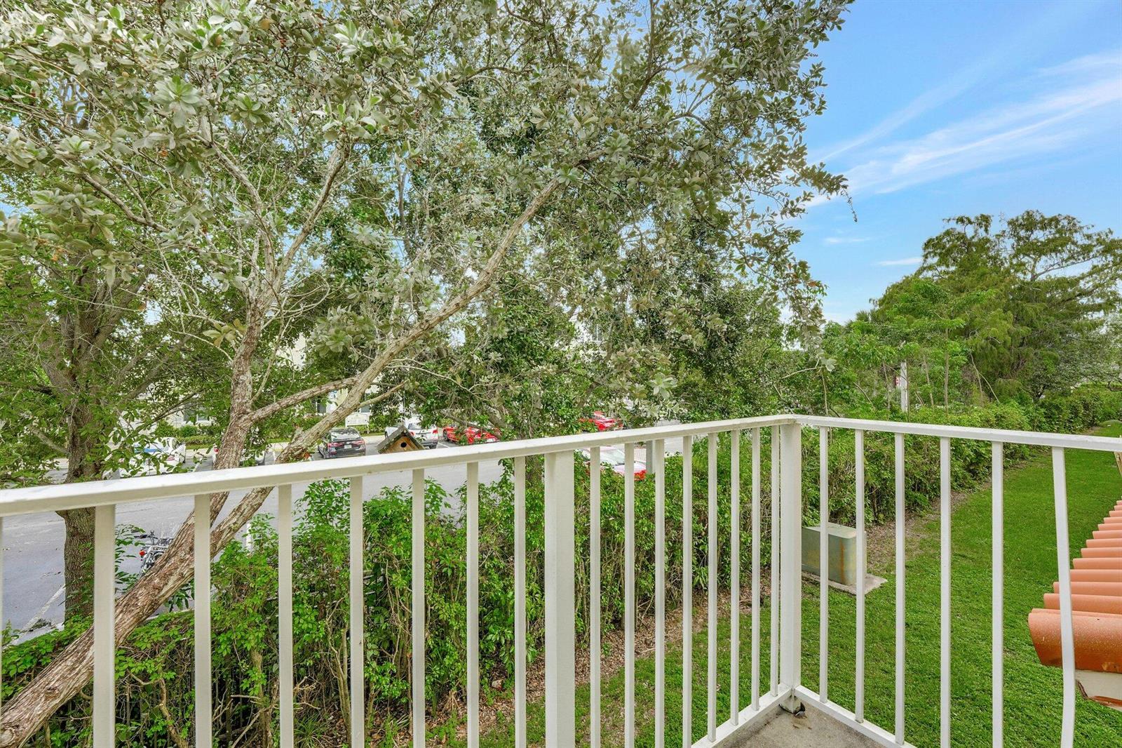 A view from a balcony overlooking a parking lot, trees, and a grassy area — 3832 NW 90th Avenue # 3832, Sunrise FL 33351, SUNRISE, FL