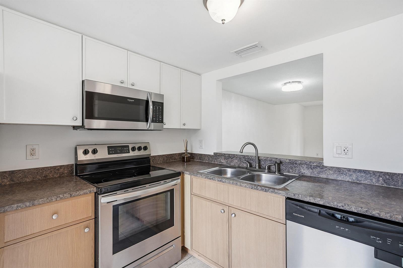 A kitchen features stainless steel appliances, light wood cabinets, white upper cabinets, and dark countertops — 3832 NW 90th Avenue # 3832, Sunrise FL 33351, SUNRISE, FL