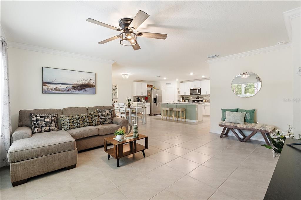 A living room with a sectional sofa, coffee table, and open kitchen in the background — 5223 BYRONIC COURT, BROOKSVILLE, FL