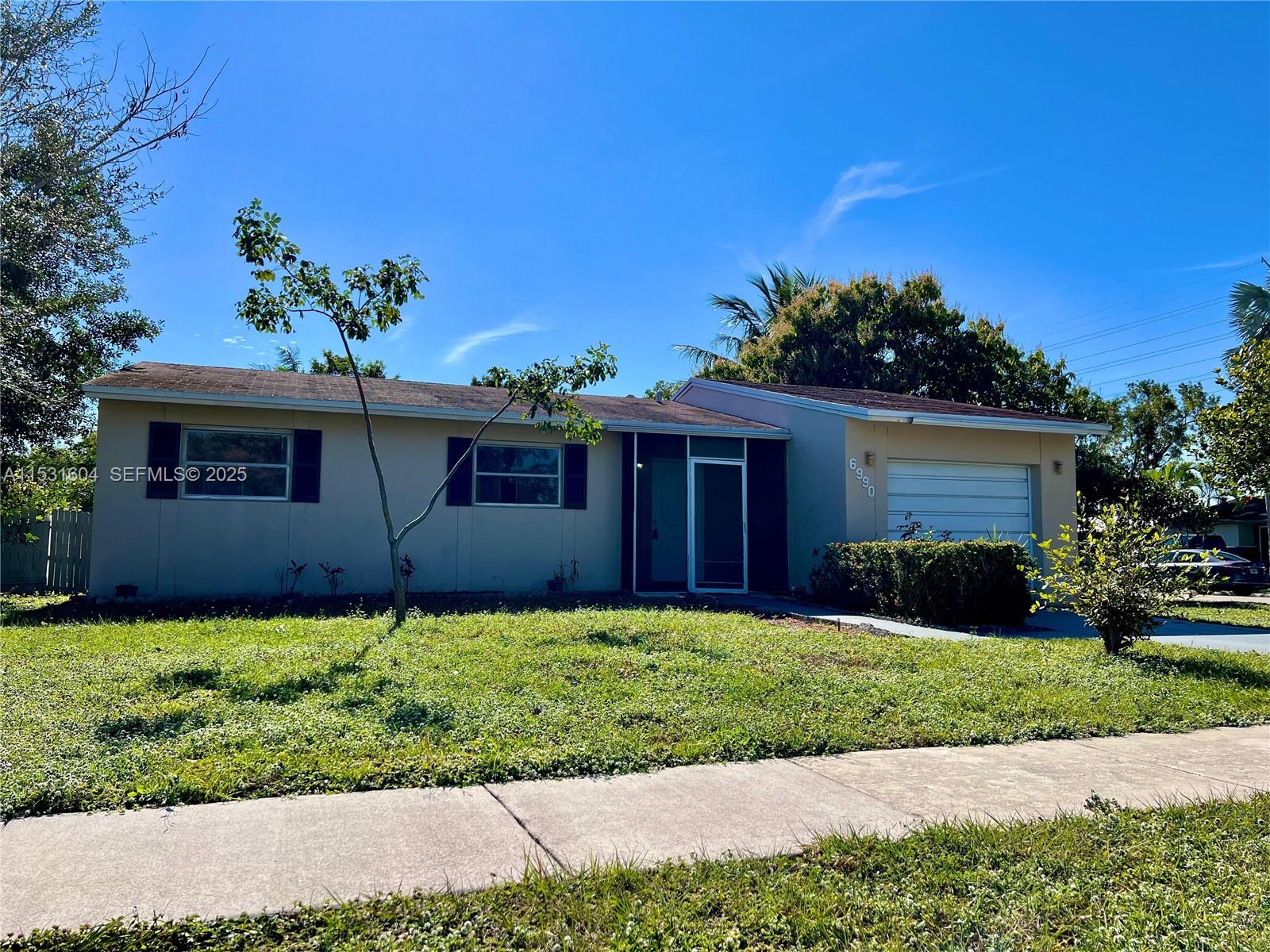 A single-story house with a beige exterior, a garage, and a front lawn under blue sky — 6990 SW 1st St, Margate FL 33068, MARGATE, FL