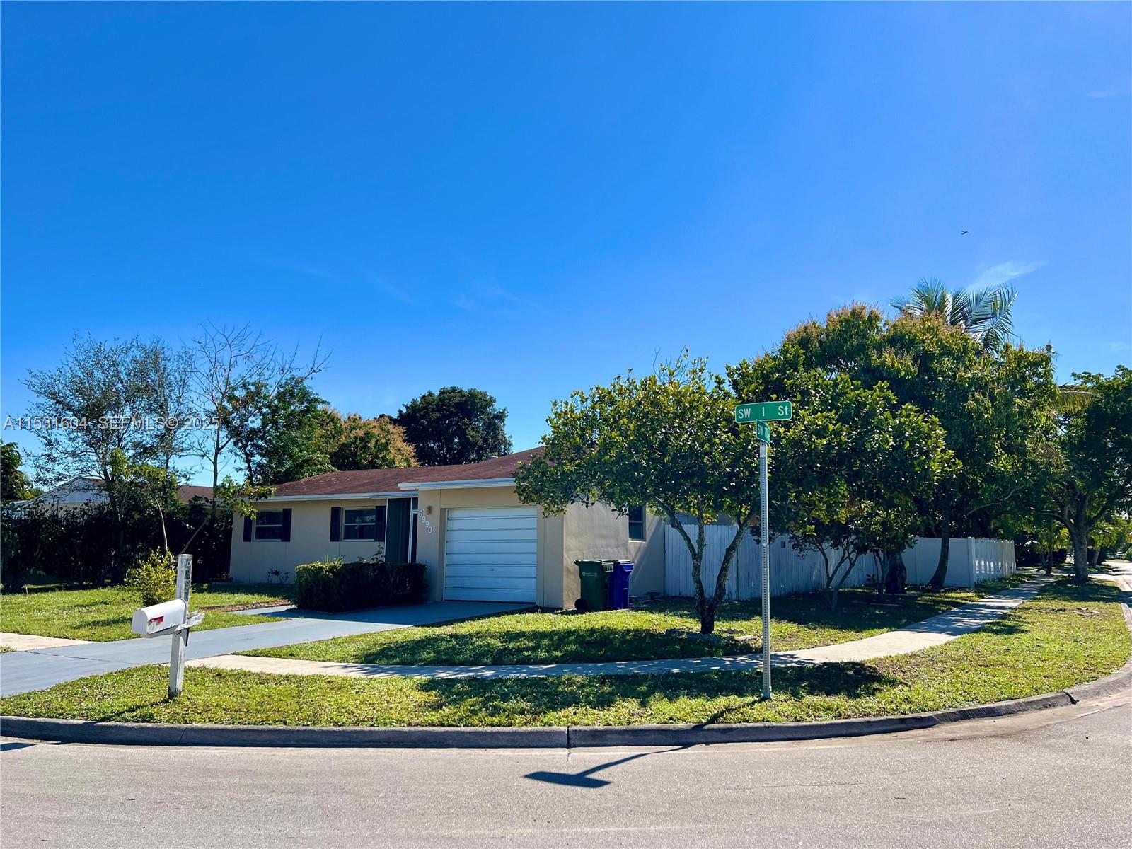 A single-story house with a white garage and a mailbox sits on a corner lot — 6990 SW 1st St, Margate FL 33068, MARGATE, FL