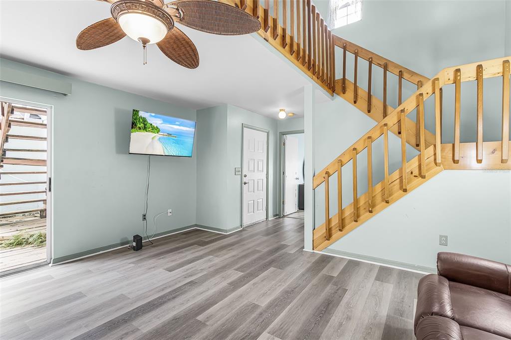 A living room with light blue walls, wood-look flooring, a staircase, and a ceiling fan — 13721 MARKHAM LANE UNIT 4, FORT MYERS, FL