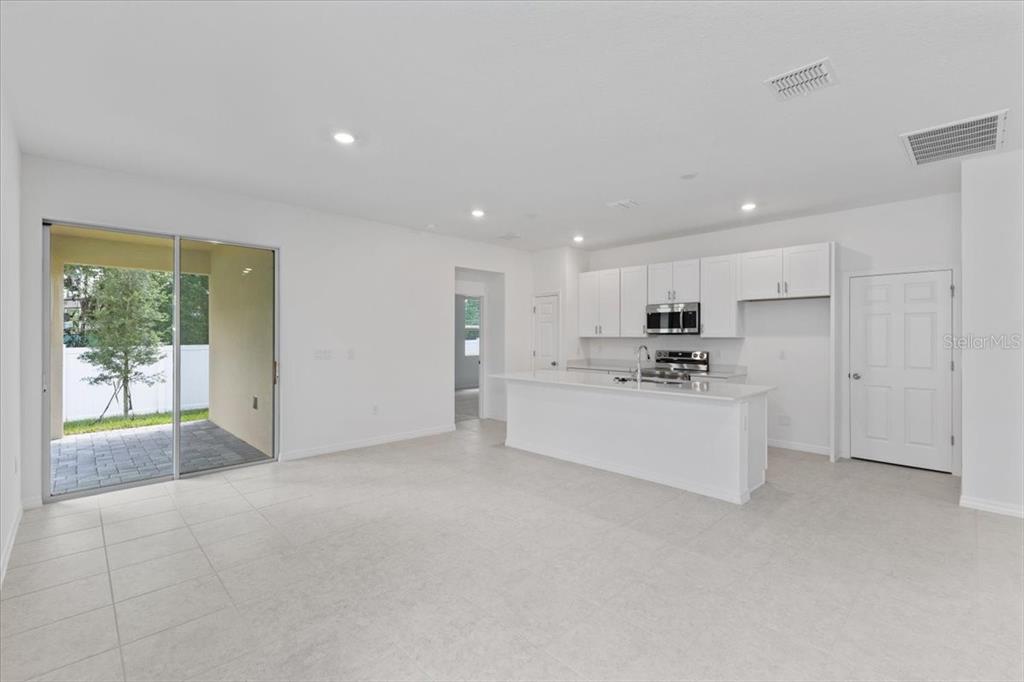 A bright, open-concept kitchen and living area features white cabinetry, a central island, and tile flooring — 1194 ATLANTIC AVENUE, FRUITLAND PARK, FL