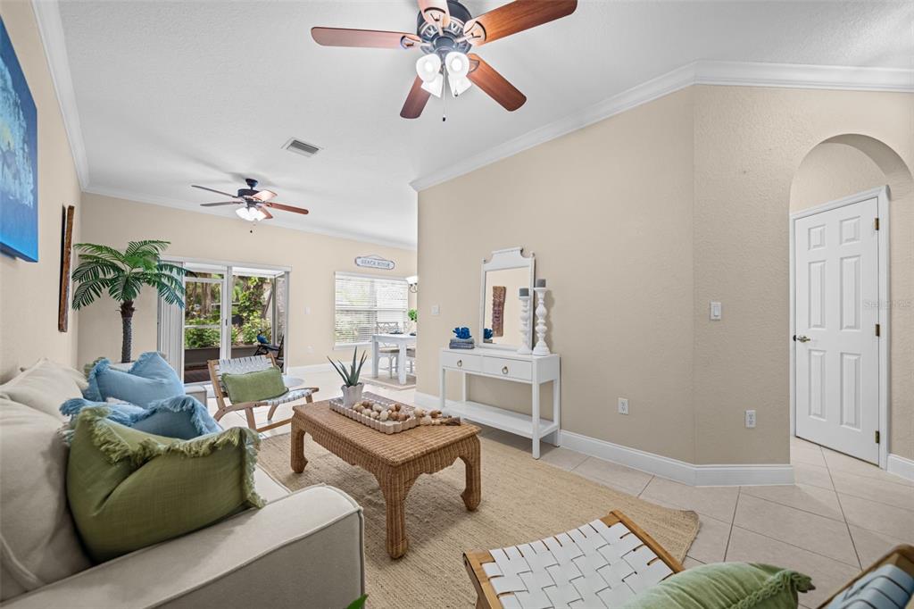 A bright living room features a beige sofa, wicker coffee table, and ceiling fans — 202 KING NEPTUNE LANE UNIT 202, CAPE CANAVERAL, FL