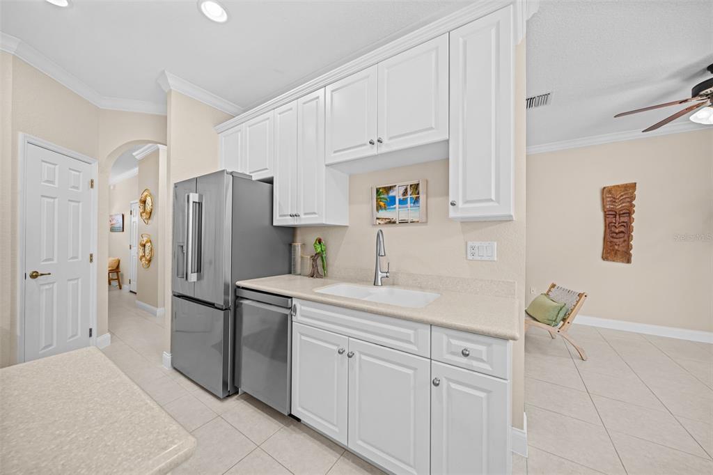 A kitchen wet bar features white cabinets, stainless steel appliances, and a beige countertop — 202 KING NEPTUNE LANE UNIT 202, CAPE CANAVERAL, FL