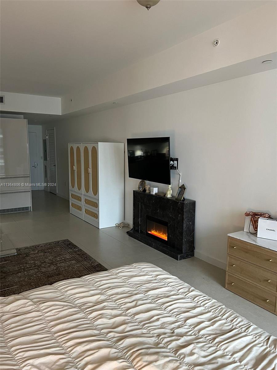 A bedroom features a bed, a wall-mounted television above a fireplace, and a storage cabinet — 1010 Brickell Ave # 2010, Miami FL 33131, MIAMI, FL