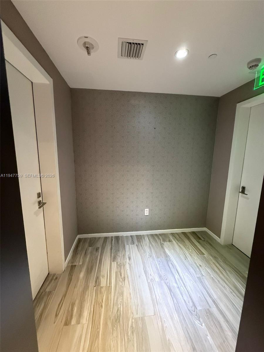 A small room features gray patterned wallpaper, light wood-look flooring, and two white doors — 801 S Miami Ave # 1804, Miami FL 33130, MIAMI, FL
