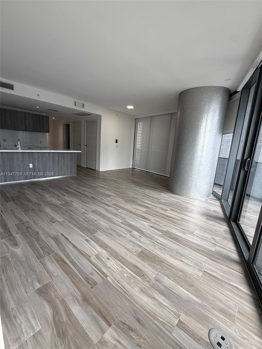 An open-concept living area features wood-look tile flooring, a kitchen island, and a structural column — 801 S Miami Ave # 1804, Miami FL 33130, MIAMI, FL