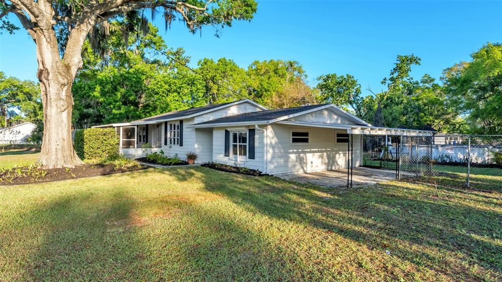 A single-story house with white siding, a carport, and a large tree in the yard — 1317 W BELMAR STREET, LAKELAND, FL