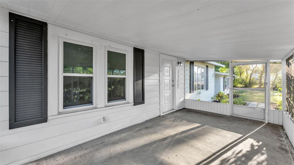 A covered concrete porch features white siding, black shutters, and a screen door — 1317 W BELMAR STREET, LAKELAND, FL
