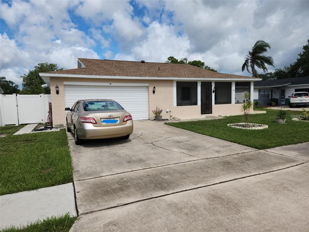 A single-story beige brick house with a two-car garage and a concrete driveway — 2518 BOWMER DRIVE, KISSIMMEE, FL
