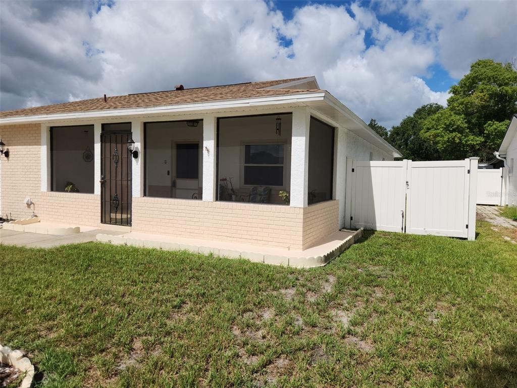 A single-story house with a screened-in porch, brick siding, and a white vinyl privacy fence — 2518 BOWMER DRIVE, KISSIMMEE, FL