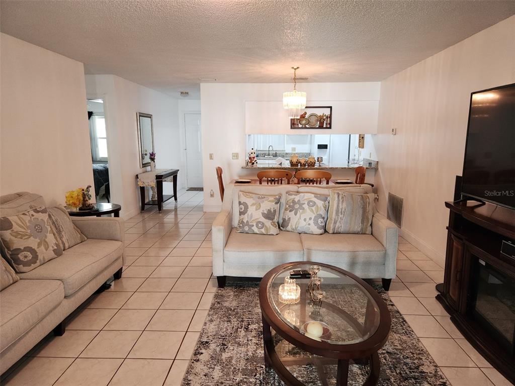 A living room with tile floors, a sofa, and a dining area with a kitchen pass-through — 2518 BOWMER DRIVE, KISSIMMEE, FL