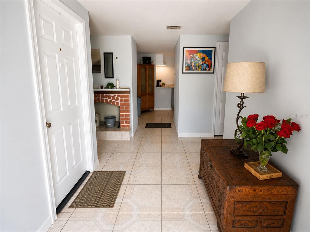 An entryway with tile flooring, a brick fireplace, and a wooden chest with flowers — 5801 BROOKGREEN AVENUE, ORLANDO, FL