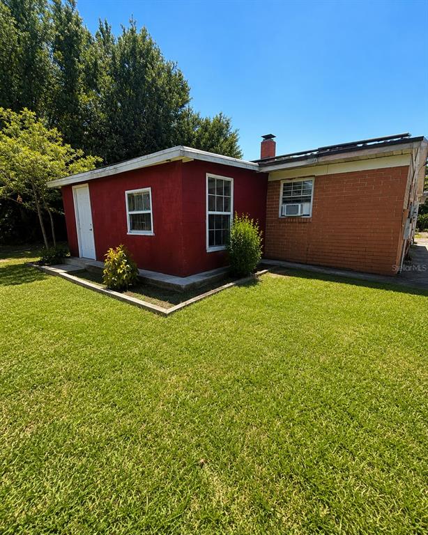 The exterior of a house featuring red stucco walls, brick siding, and a chimney — 5801 BROOKGREEN AVENUE, ORLANDO, FL