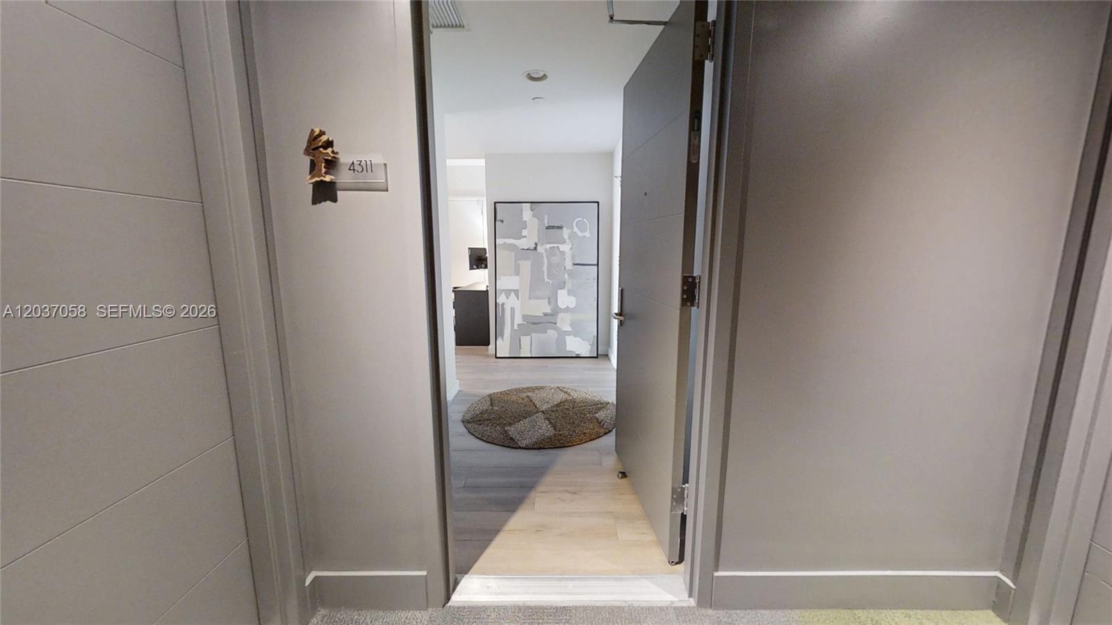 The view through an open doorway reveals an entryway with light wood flooring and artwork — 1010 Brickell Ave # 4311, Miami FL 33131, MIAMI, FL