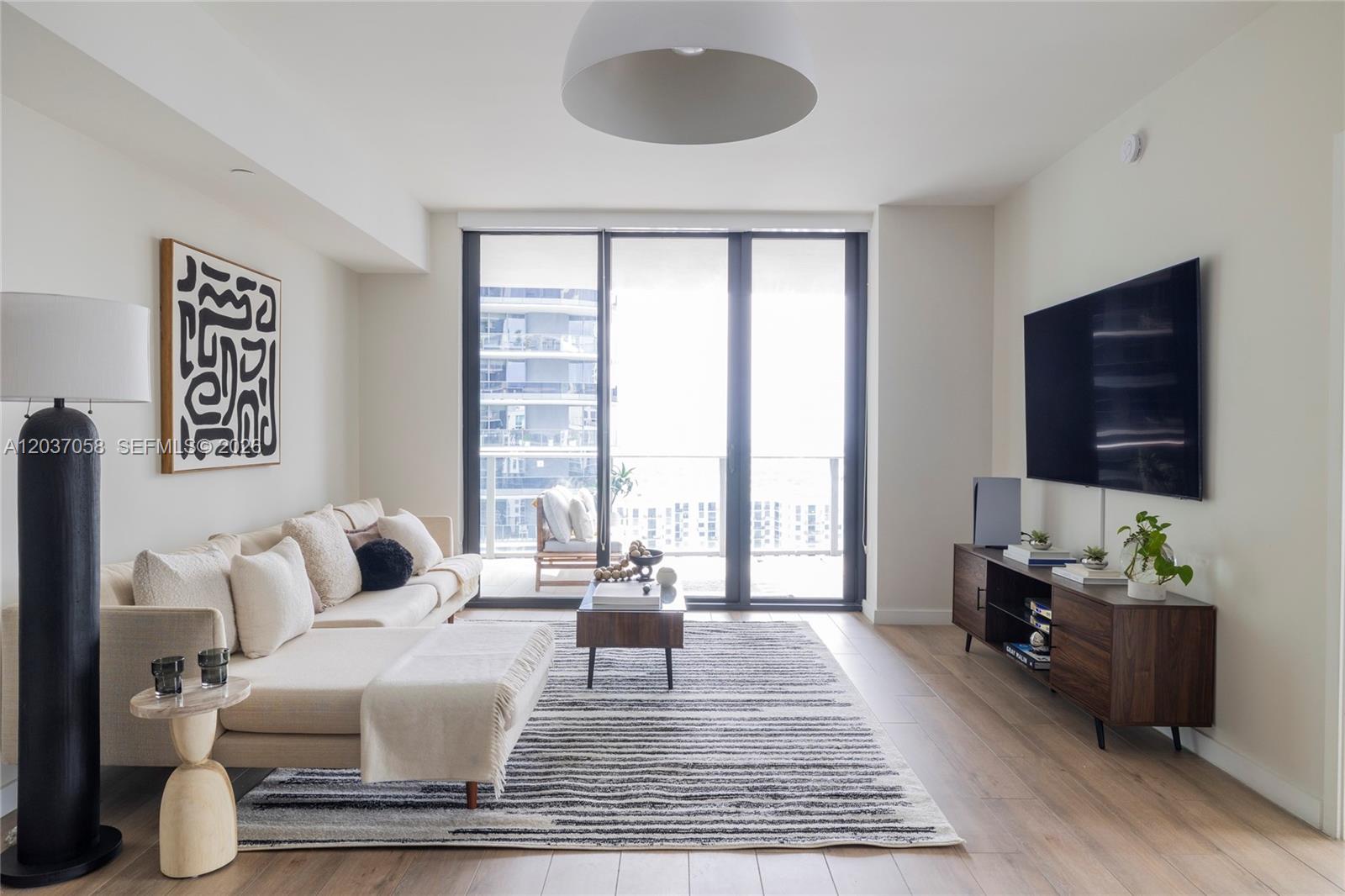 A modern living room features a beige sectional sofa, striped rug, and a wall-mounted television — 1010 Brickell Ave # 4311, Miami FL 33131, MIAMI, FL