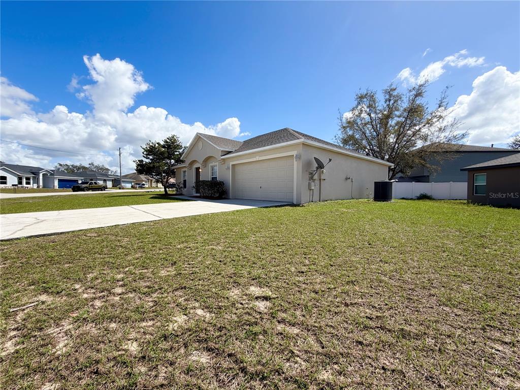 A single-story house with a beige stucco exterior, a two-car garage, and a concrete driveway — 1914 MANATEE COURT, KISSIMMEE, FL