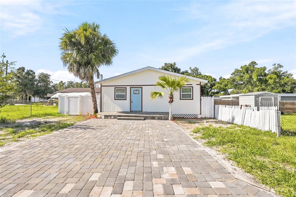A single-story house with white siding, a blue front door, and a paved driveway — 1313 E SITKA STREET, TAMPA, FL
