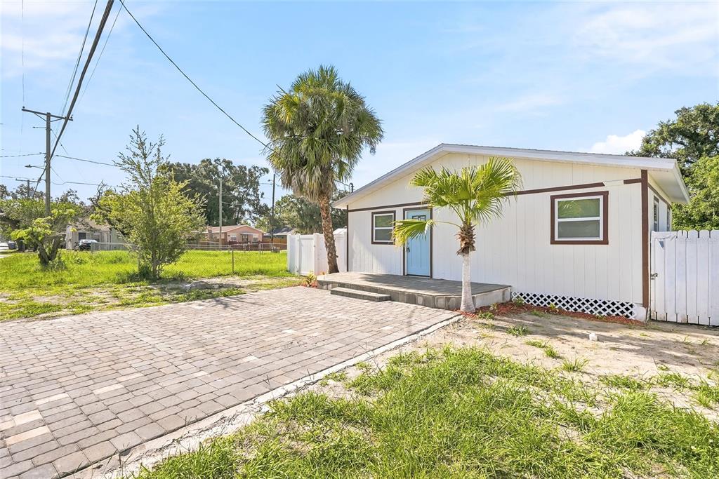 A single-story house with white siding, a paved driveway, and two palm trees — 1313 E SITKA STREET, TAMPA, FL