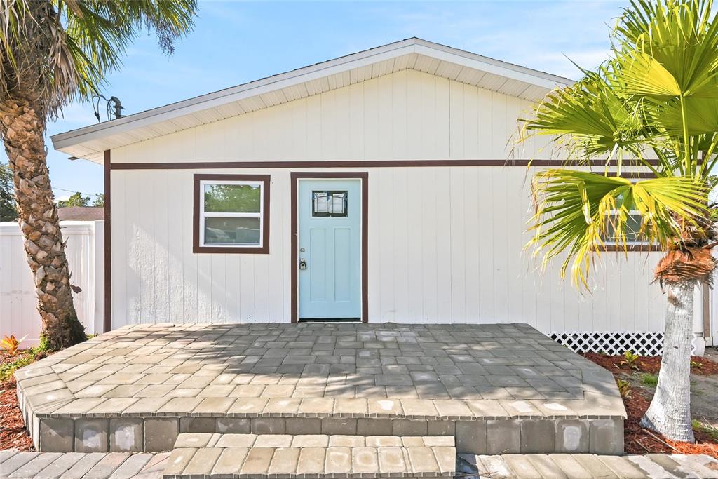 A light-colored house exterior features a light blue front door and a stone patio — 1313 E SITKA STREET, TAMPA, FL