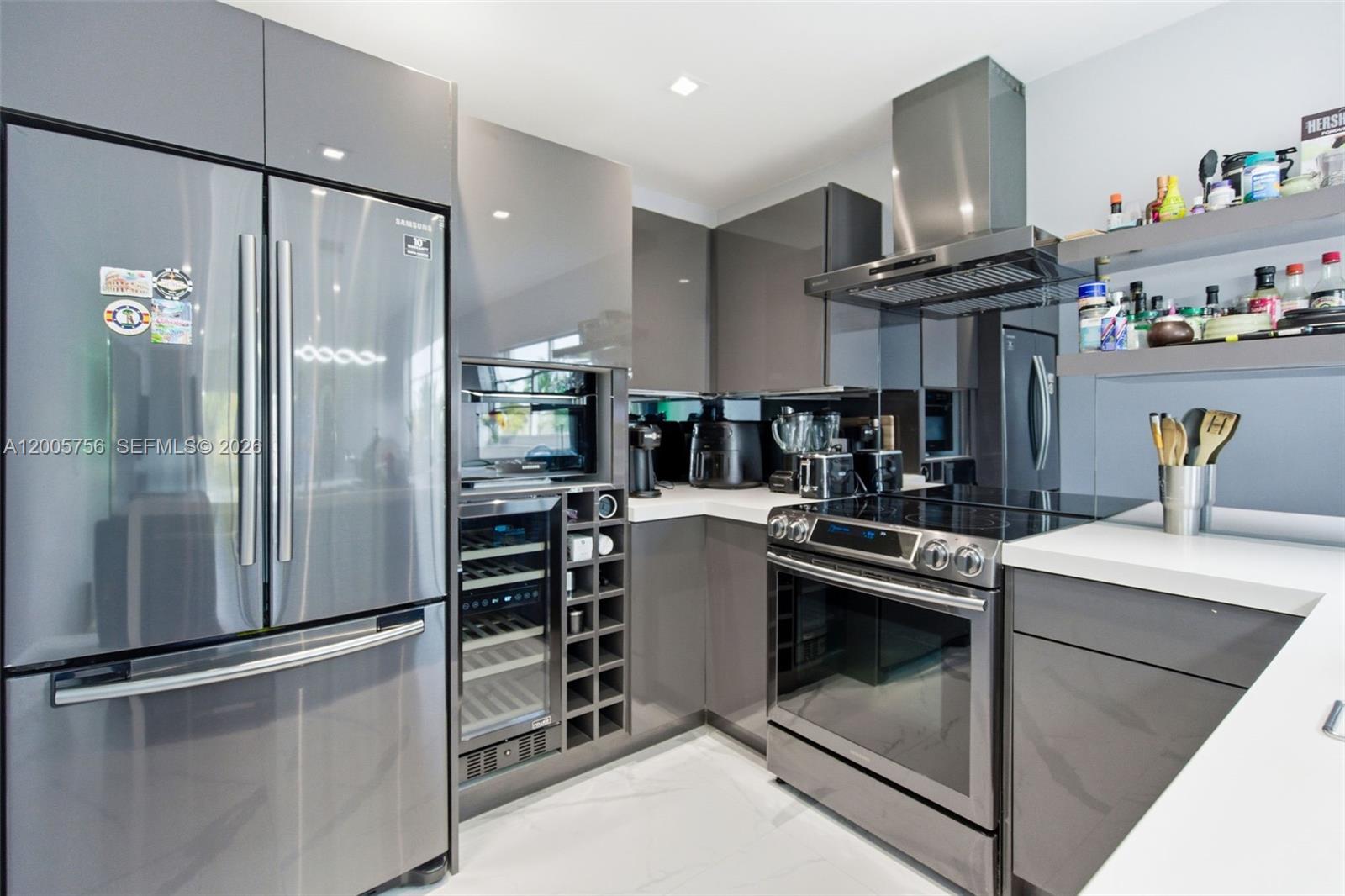 A modern kitchen features gray glossy cabinetry, stainless steel appliances, and white countertops — 1428 Euclid Ave # 207, Miami Beach FL 33139, MIAMI BEACH, FL