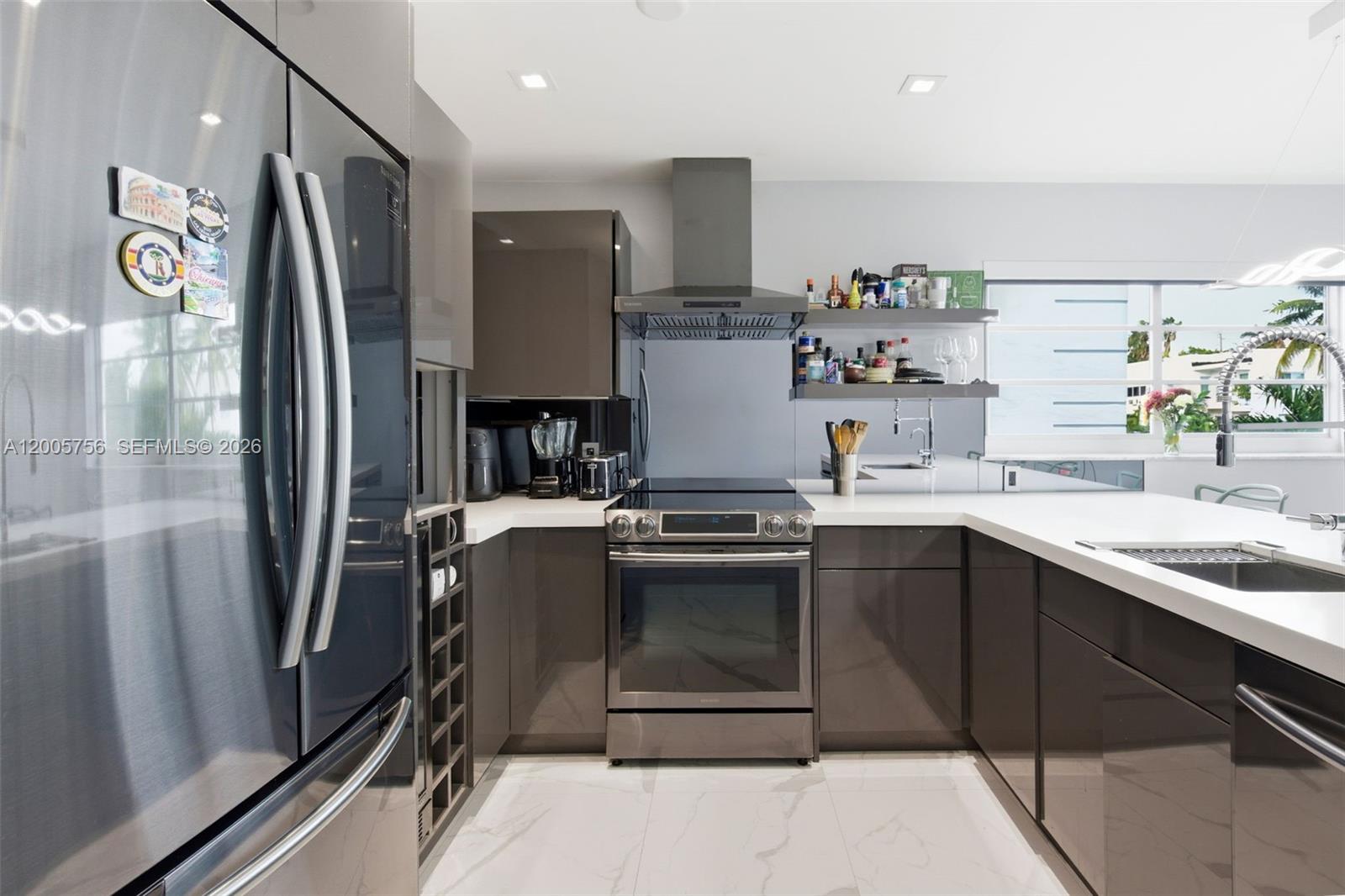 A modern kitchen features glossy gray cabinets, stainless steel appliances, and white countertops — 1428 Euclid Ave # 207, Miami Beach FL 33139, MIAMI BEACH, FL