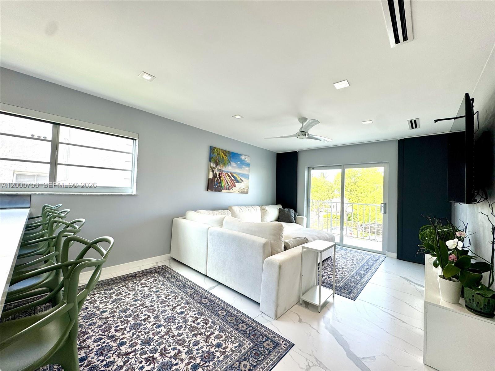 A living room features a white sectional sofa, marble floors, and a balcony view — 1428 Euclid Ave # 207, Miami Beach FL 33139, MIAMI BEACH, FL