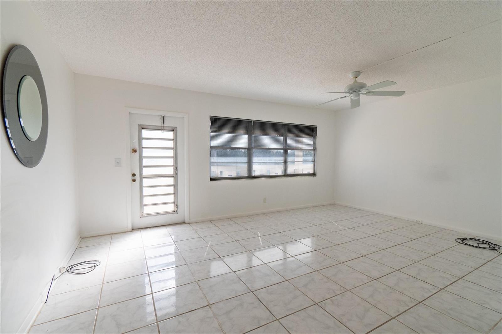 An empty room with white walls, white tile flooring, a ceiling fan, and a glass door — 4035 Cambridge B # 4035, Deerfield Beach FL 33442, DEERFIELD BEACH, FL