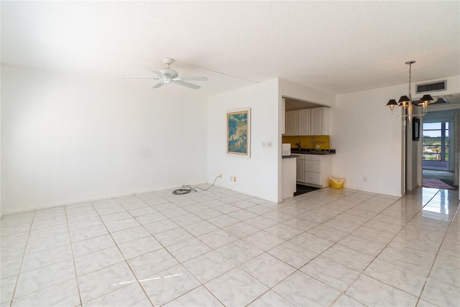 An open-concept living and dining area features white tile flooring, a ceiling fan, and kitchen — 4035 Cambridge B # 4035, Deerfield Beach FL 33442, DEERFIELD BEACH, FL