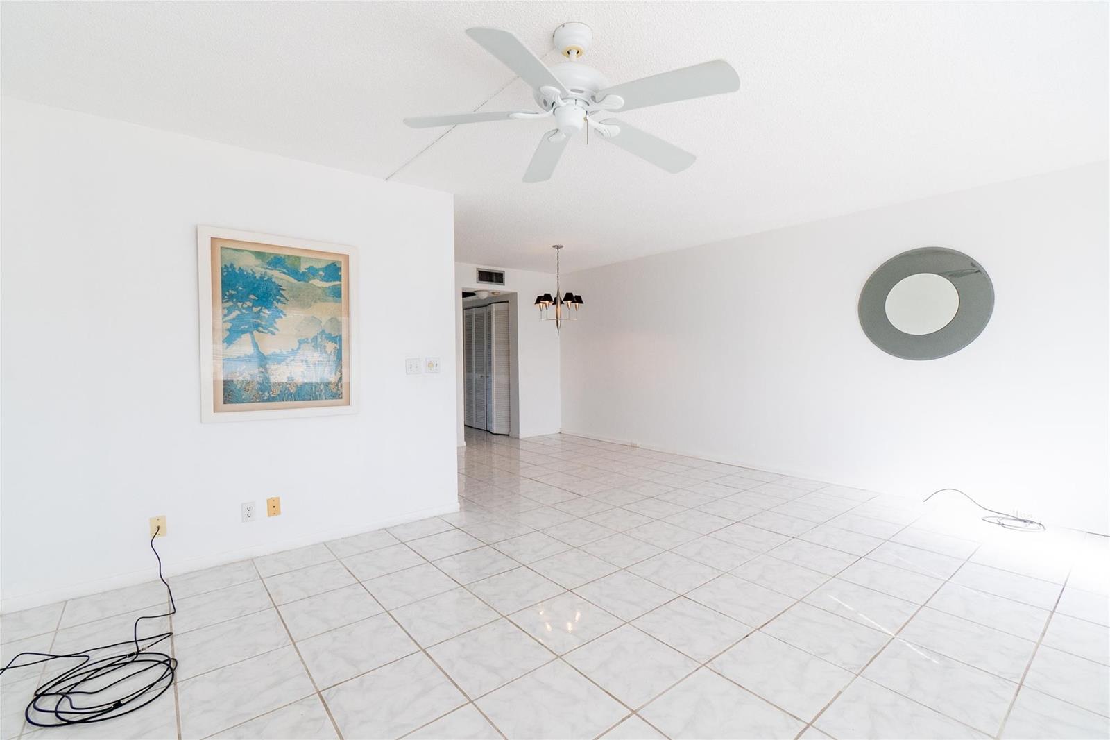 An empty room with white walls, white tile flooring, a ceiling fan, and a mirror — 4035 Cambridge B # 4035, Deerfield Beach FL 33442, DEERFIELD BEACH, FL