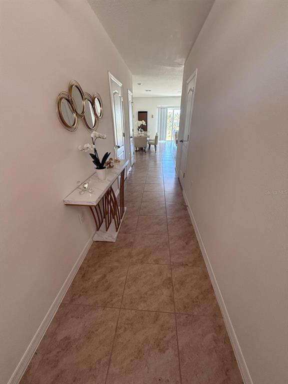 A tiled hallway leads from the entryway toward a dining area and sliding glass doors — 1419 PLANK PLACE, DAVENPORT, FL
