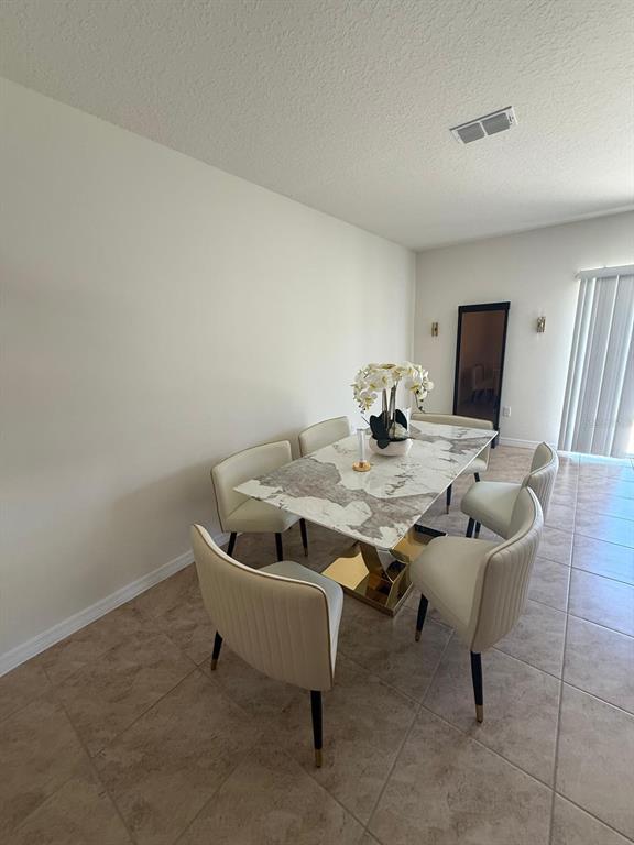 A dining room features a marble-topped table with gold base and six cream-colored chairs — 1419 PLANK PLACE, DAVENPORT, FL