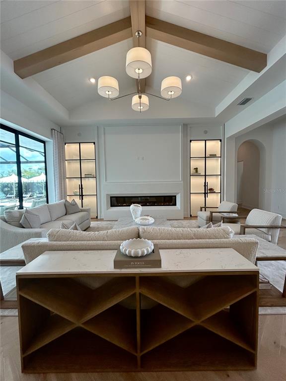 A living room features a vaulted ceiling with wood beams, a fireplace, and built-in shelving — 258 CRYSTAL WATERS DRIVE, SARASOTA, FL