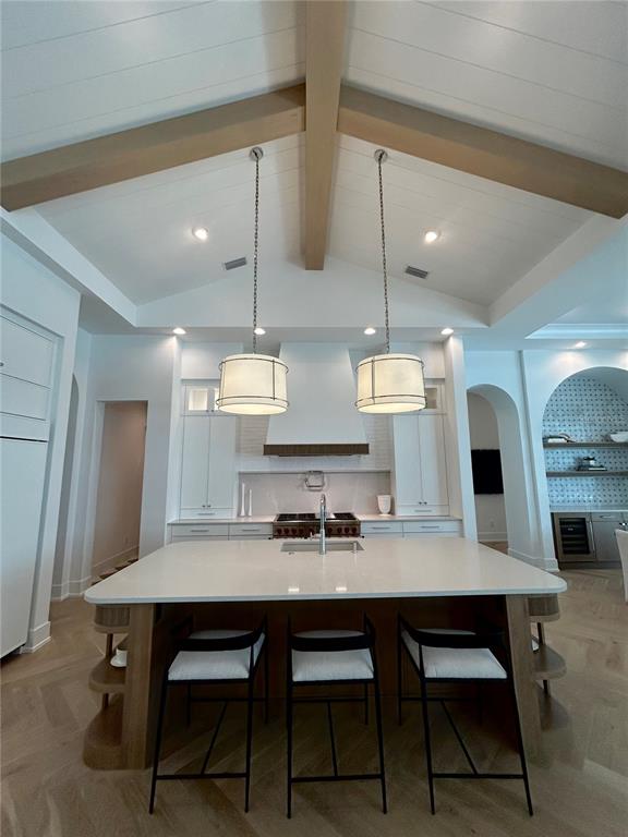 A kitchen features a large island, pendant lighting, and vaulted ceilings with exposed wooden beams — 258 CRYSTAL WATERS DRIVE, SARASOTA, FL