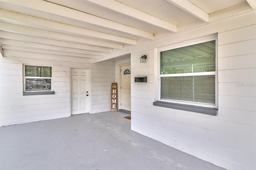 A single-story white house features a front carport, a concrete driveway, and a wooden fence — 2804 N 33RD STREET, TAMPA, FL