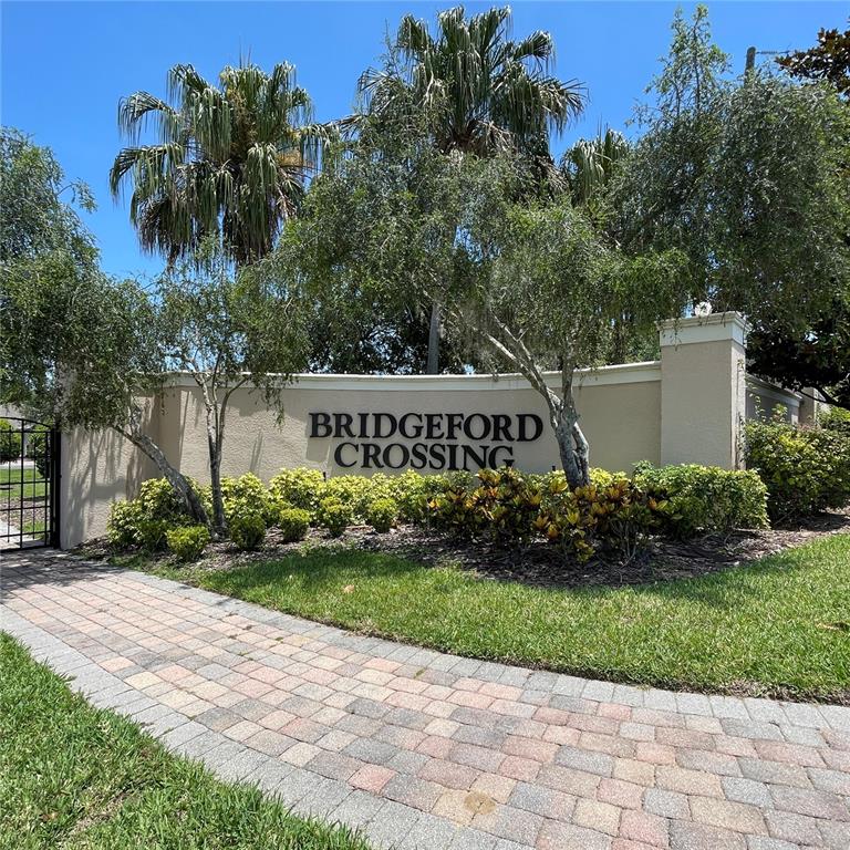 A beige stucco wall displays the Bridgeford Crossing community sign behind a brick walkway — 845 BRIDGEFORD CROSSING BOULEVARD, DAVENPORT, FL