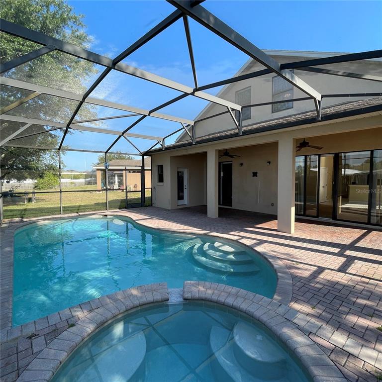 A screened-in patio features a swimming pool, a spa, and a paved deck — 845 BRIDGEFORD CROSSING BOULEVARD, DAVENPORT, FL