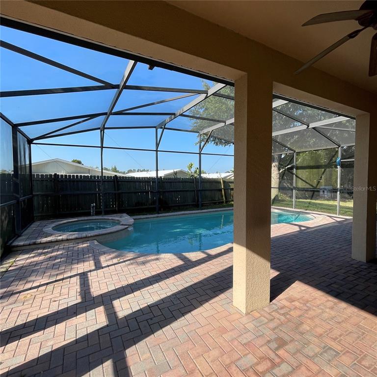 A screened-in patio features a brick paver floor, a swimming pool, and a hot tub — 845 BRIDGEFORD CROSSING BOULEVARD, DAVENPORT, FL