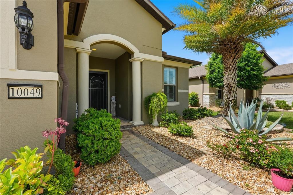 The exterior of a house features a stone walkway leading to a covered entryway — 10049 SW 77TH LOOP, OCALA, FL