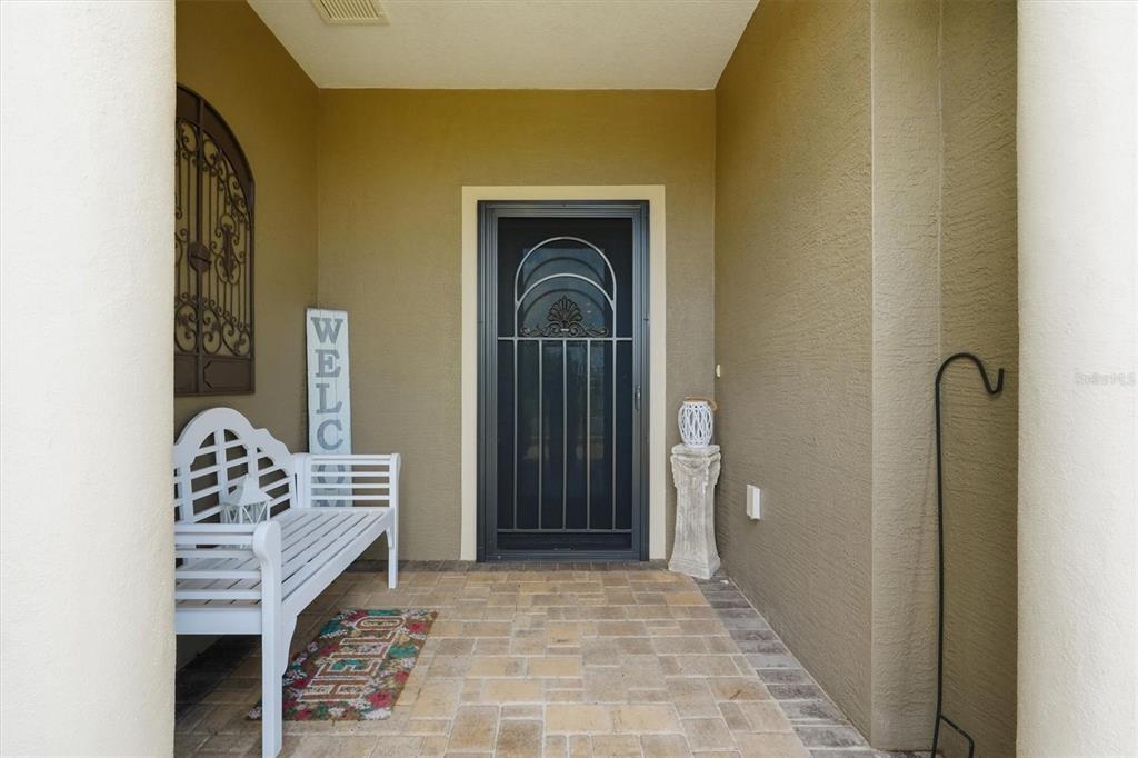 A covered front porch features a white bench, a welcome sign, and a screen door — 10049 SW 77TH LOOP, OCALA, FL