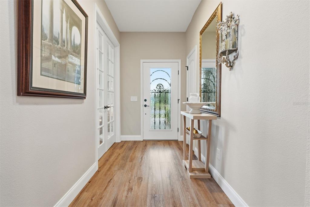 A bright entryway features wood-look flooring, a glass-paneled front door, and a console table — 10049 SW 77TH LOOP, OCALA, FL